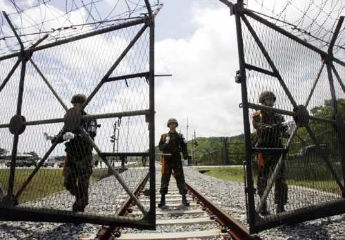 South Korean soldiers open a gate for a North Korean train at the demilitarized zone (DMZ) in Goseong, east of Seoul May 17, 2007. Two trains from North and South Korea crossed the heavily armed border on Thursday, restoring for the first time an artery severed in the 1950-1953 fratricidal war and fanning dreams of unification. It took the two Koreas 56 years to send the trains -- one starting in the South and one in the North -- across the Cold War's last frontier for the runs of about 25 km (15 miles). REUTERS/Ahn Young-joon/Pool (SOUTH KOREA)